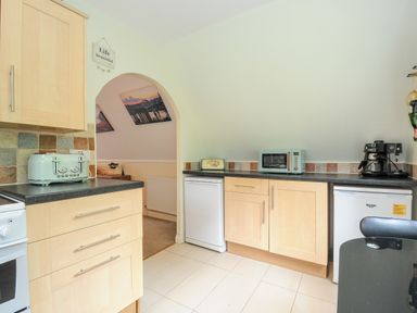A kitchen with wooden cabinets a microwave coffee maker and toaster at Dart Lodge in Callington