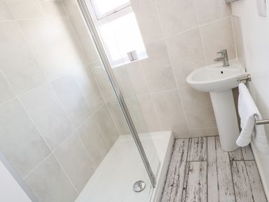 A bathroom with a glass shower enclosure a pedestal sink and a towel on a rack at Rock Pool House in Porthleven
