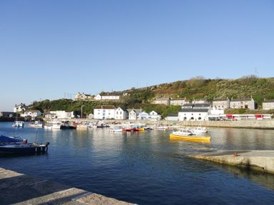 A harbor with boats moored near a quay and buildings on a hillside at Rock Pool House in Porthleven
