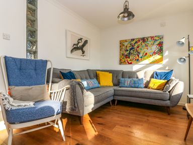A living room with a grey sectional sofa with cushions and a blue armchair with a cushion and blanket