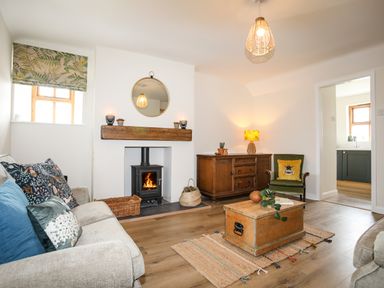 A living room with a fireplace wooden chest coffee table sofa and wooden cabinet at Plas Coch Rhoscolyn in Rhoscolyn