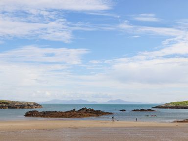 A beach with rocks and people near the water at Plas Coch Rhoscolyn in Rhoscolyn