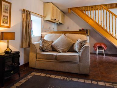 A living room with beige sofa and cushions under wooden stairs at The Stable in Fethard-On-Sea County Wexford