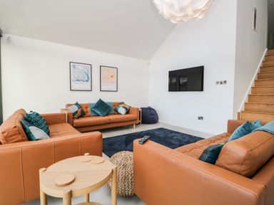 A living room with orange sofas and a wall-mounted television at Kessock in Bowness-On-Windermere