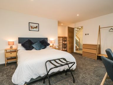 A bedroom with a double bed with pillows bedside tables lamps wardrobe and a chair at Kessock in Bowness-On-Windermere