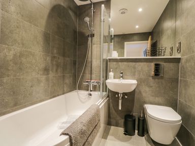 A bathroom with a bathtub shower sink and toilet at Kessock in Bowness-On-Windermere