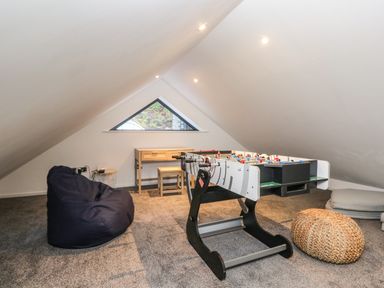 A games room with a foosball table bean bag and small desk under a triangular window at Kessock in Bowness-On-Windermere