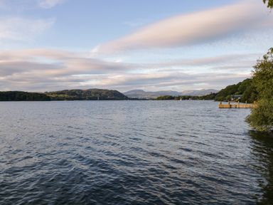 A large body of water with hills and trees in the background and a dock on the right side at Kessock in Bowness-On-Windermere