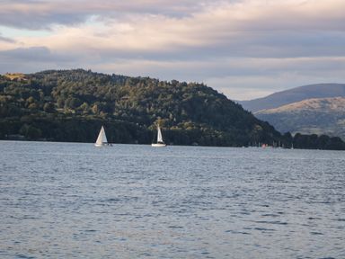 A lake with sailboats and tree-covered hills in the background at Kessock in Bowness-On-Windermere