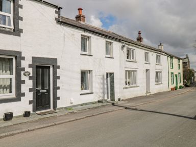 A row of terraced houses with white walls and black and green door and window frames on a street