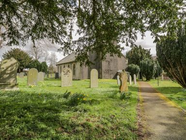 A cemetery with tombstones and trees beside a pathway near a building at Sparrow Cottage in Keswick
