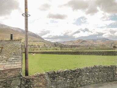 A rural landscape with green fields stone walls sheep and hills in the background at Sparrow Cottage in Keswick