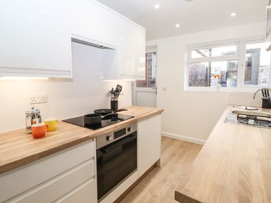 A kitchen with wooden countertops white cabinets cooking utensils and a window at Sparrow Cottage in Keswick