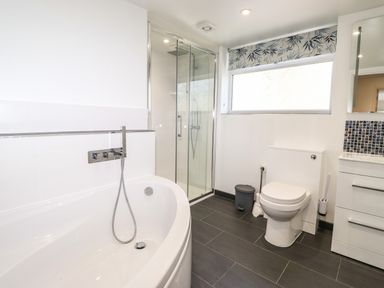 A bathroom with a bathtub shower toilet and sink at Sparrow Cottage in Keswick
