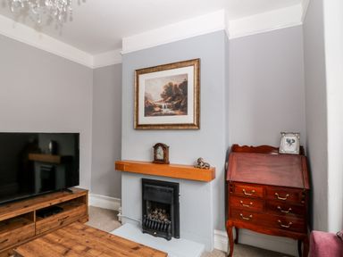 A living room with a fireplace wooden TV stand and a wooden cabinet at Daisy Cottage in Bideford