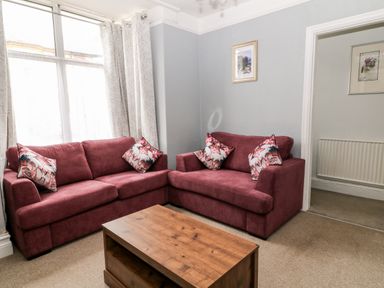 A living room with two red sofas and a wooden coffee table at Daisy Cottage in Bideford