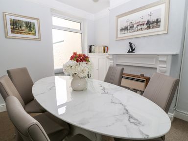 A dining room with a marble table and chairs and a vase of flowers on the table at Daisy Cottage in Bideford
