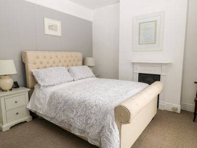 A bedroom with a bed lamps two paintings and a fireplace at Daisy Cottage in Bideford