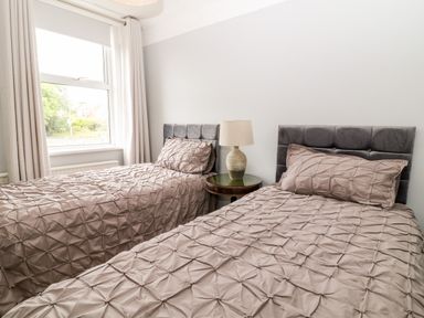 A bedroom with two single beds and a bedside table with a lamp at Daisy Cottage in Bideford