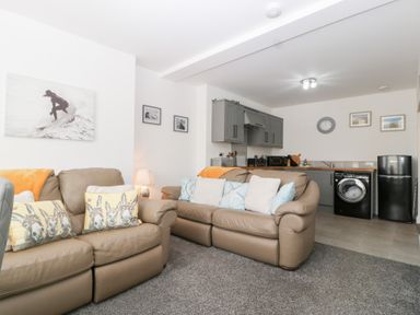 A living room with couches and a kitchen area at 76A Mackworth Road in Porthcawl