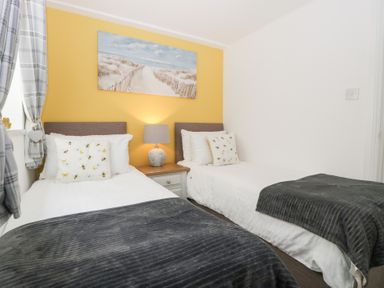 A bedroom with two single beds and a lamp on a nightstand at 76A Mackworth Road Porthcawl