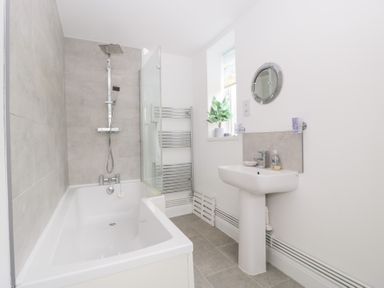 A bathroom with a bathtub, shower, sink, and towel rail at 76A Mackworth Road, Porthcawl