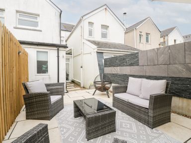 A garden with seating and a coffee table at 76A Mackworth Road in Porthcawl