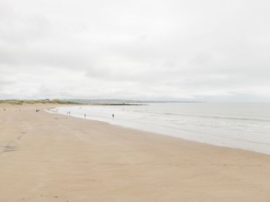 A beach with people walking along the shore at 76A Mackworth Road Porthcawl