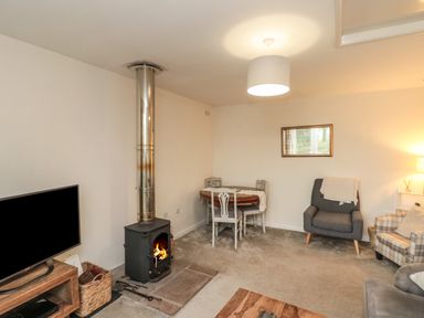 A living room with a wood stove and a dining table with chairs at Chestnut Cottage in Filey