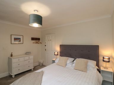 A bedroom with a double bed a headboard bedside tables with lamps and a chest of drawers at Chestnut Cottage in Filey