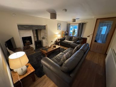 A living room with two leather sofas a wooden coffee table a fireplace and a small decorated Christmas tree at Weavers Cottage in Tremadog