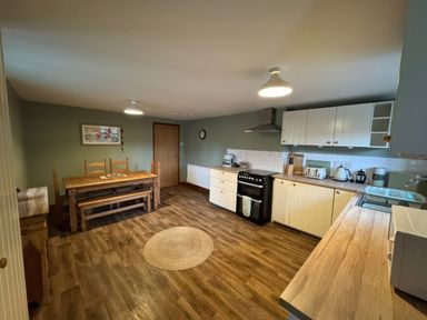 A kitchen and dining area with wooden furniture white cabinets and appliances at Weavers Cottage in Tremadog