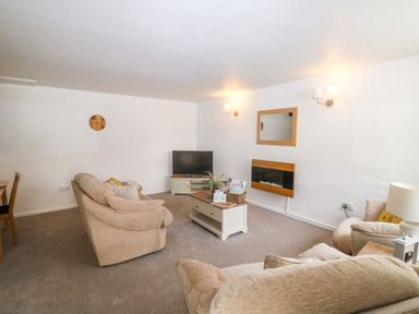 A living room with sofas coffee table tv and wall mirror at Rose Cottage in Marldon