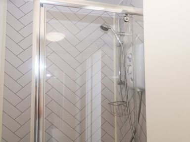 A shower area with a handheld showerhead and control panel in a tiled bathroom at Rose Cottage in Marldon
