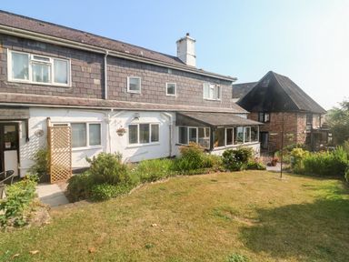 Exterior view of a two story house with garden and shrubbery at Rose Cottage in Marldon