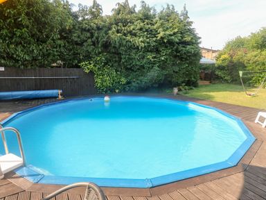 An outdoor circular swimming pool with a metal ladder and a beach ball floating on the water at Rose Cottage in Marldon