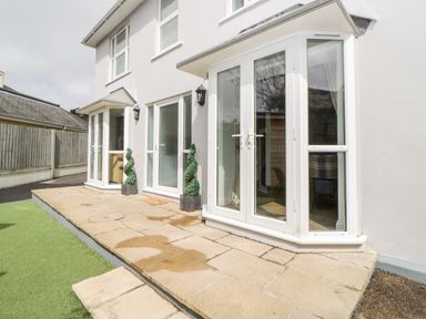 The exterior of a white two-story house with large glass doors and windows on a stone patio at Fonthill in Torquay