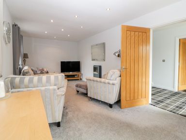 A living room with striped sofas a television on a wooden stand a mirror and an open wooden door at Fonthill in Torquay