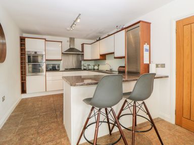 A kitchen with a breakfast bar with two stools and built in appliances at Fonthill in Torquay