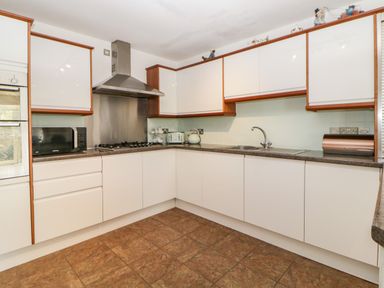 A kitchen with white cabinets a microwave a toaster a kettle a stove with a range hood and a sink at Fonthill in Torquay