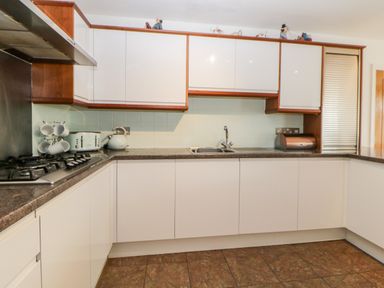 A kitchen with white cabinets a gas stove a kettle a toaster a bread box and a sink at Fonthill in Torquay