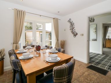 A dining room with a wooden table set for six and plaid upholstered chairs at Fonthill in Torquay