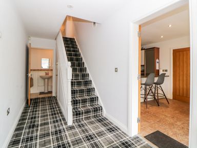 A hallway with a carpeted staircase and two doorways leading to a bathroom and a kitchen at Fonthill in Torquay