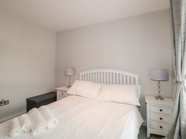 A bedroom with a white bed and pillows two bedside tables with lamps and rolled towels on the bed at Fonthill in Torquay