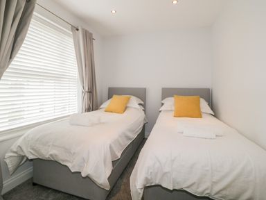A bedroom with two single beds each with a yellow pillow and folded white towels on top at Fonthill in Torquay