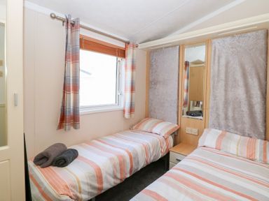 A bedroom with two single beds and a window with curtains at 109 Pentney Lakes Pentney near King's Lynn