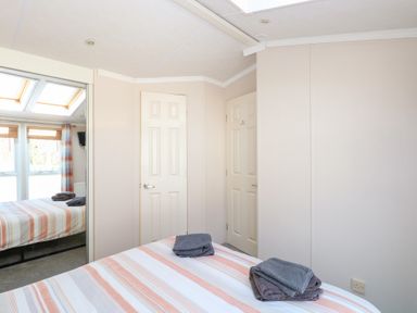 A bedroom with a striped bedspread and folded towels on the bed at 109 Pentney Lakes in Pentney near King's Lynn