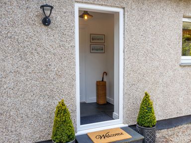 An open front door showing an entrance with an umbrella stand and two framed pictures at The Old Vicarage Retreat Luxulyan