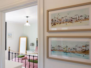 A bedroom with a black and gold metal bed frame pink and green towels a standing mirror a bedside table with a lamp and two framed pictures on the wall at The Old Vicarage Retreat in Luxulyan