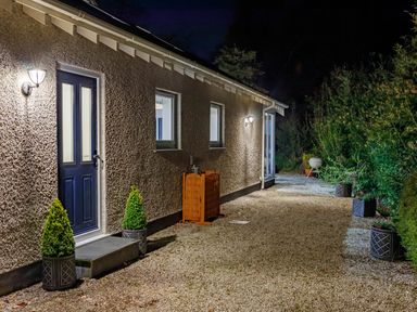 A gravel pathway beside a building with a door window and outdoor lights at The Old Vicarage Retreat in Luxulyan